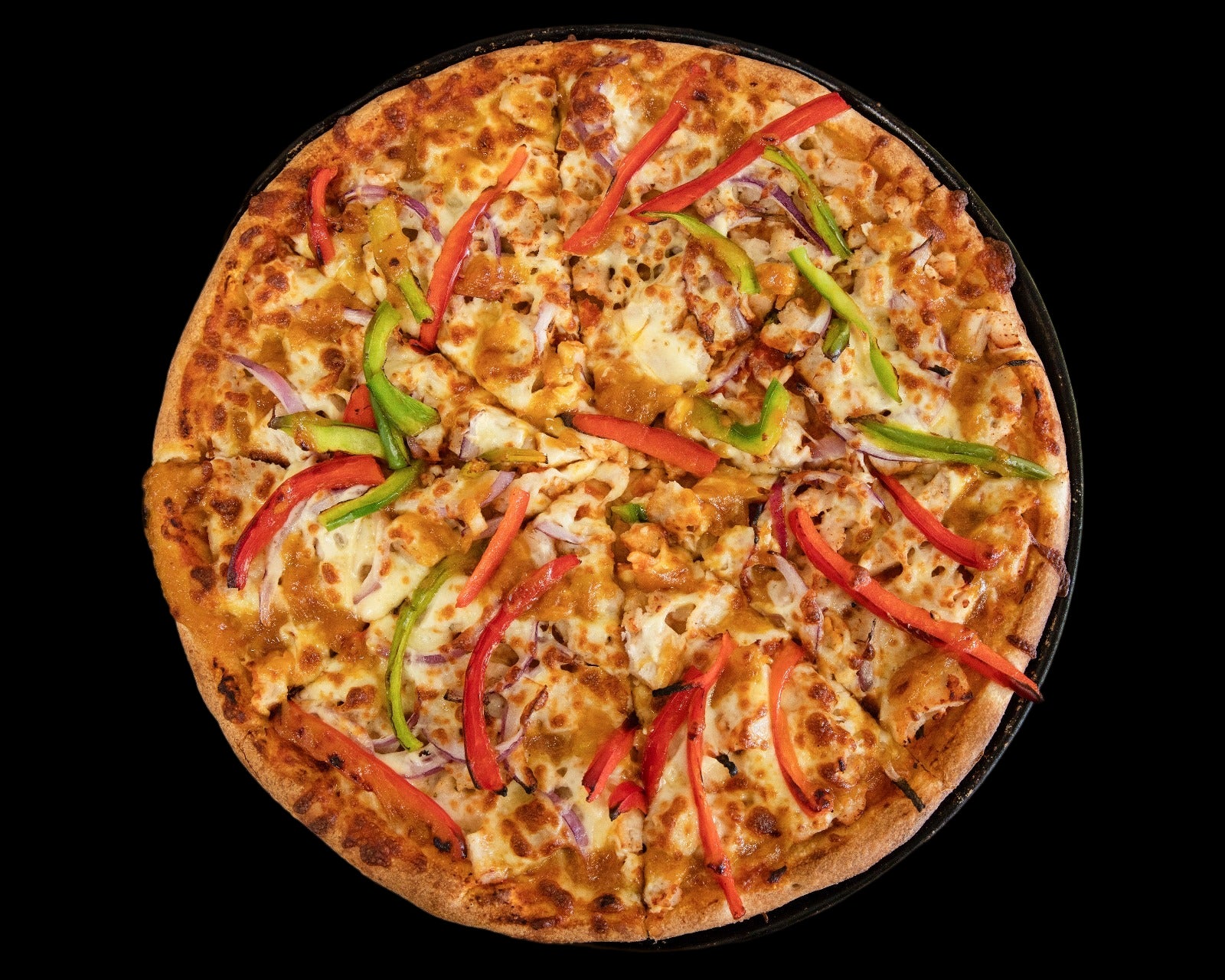 Pizza with various toppings on a black pan with a white napkin.